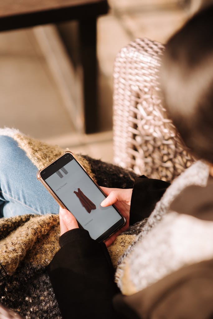 Woman using smartphone for online shopping sitting in armchair
